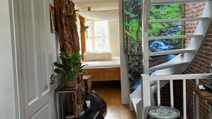 A narrow hallway with a staircase leading to a loft area. A large painting of a waterfall decorates the wall, and a plant is placed on a shelf. - Private rooftop 35m2, high-end apartment (Amsterdam)