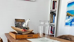 A wooden dining table with a glass pitcher, a wooden tray with fruits, and a framed picture. - Private rooftop 35m2, high-end apartment (Amsterdam)