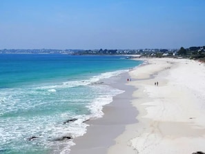 Ein Strand mit blauem Himmel, ruhiger See und Sandstrand.