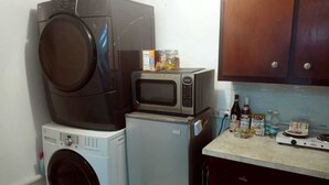 Una cocina compacta equipada con lavadora, microondas y refrigerador pequeño.
