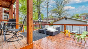 Une terrasse en bois aménagée avec du mobilier d’extérieur, notamment un canapé, des fauteuils et une table.