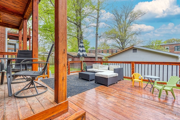 A wooden deck with outdoor furniture, including a sofa, chairs, and a table.