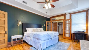 Une chambre à coucher avec un lit, une table de chevet, une lampe et un ventilateur de plafond.