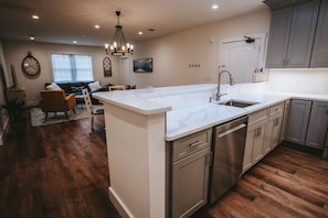 Una cocina moderna con una isla grande, electrodomésticos de acero inoxidable y un comedor con sofá y sillas.