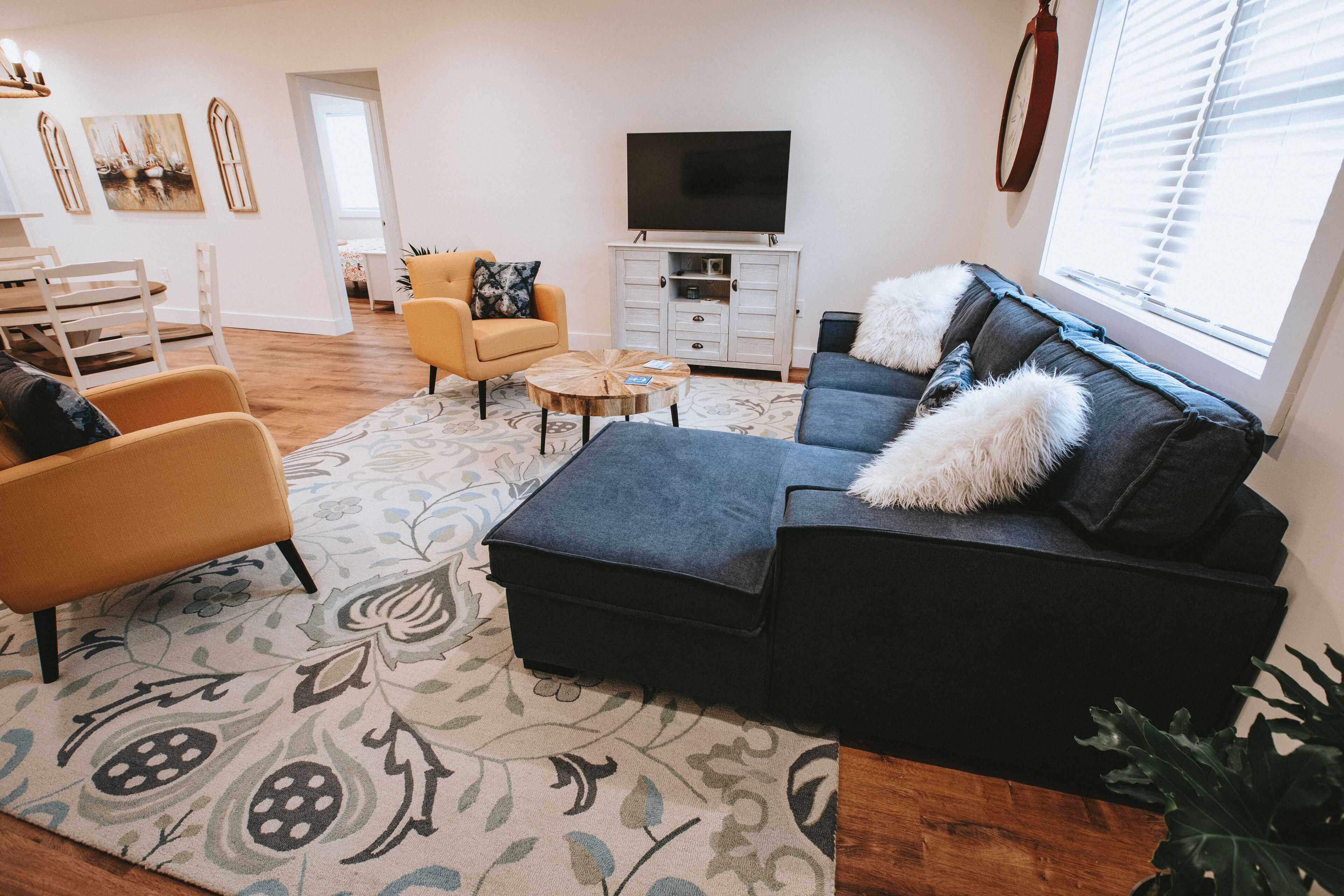 A living room with a sofa, armchairs, a coffee table, and a TV.