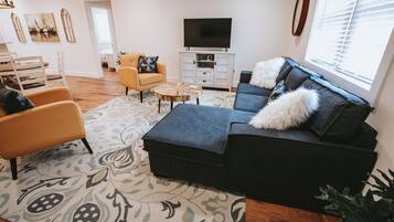 A living room with a sofa, armchairs, a coffee table, and a TV.