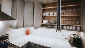 Una cucina moderna con mobili grigi, un piano di lavoro bianco e una cantinetta a incasso per il vino.