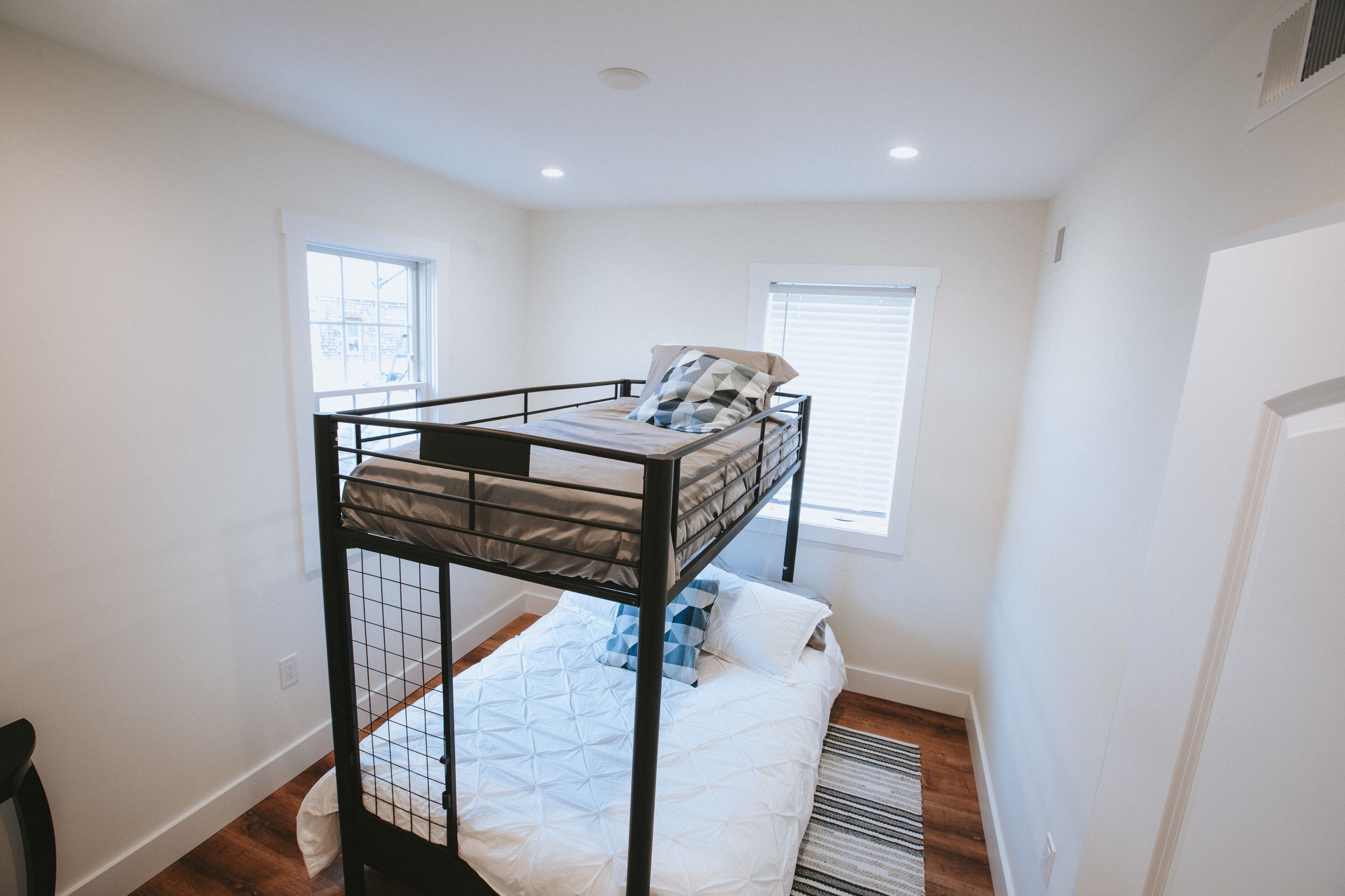 A bunk bed room with a window, a door, and a radiator.