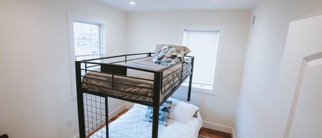 A bunk bed room with a window, a door, and a radiator.