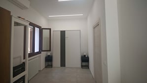 A hallway with a radiator, a mirror, a door, and a small table with a lamp.