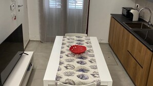 A compact kitchen with a dining table, a TV, and a sink.