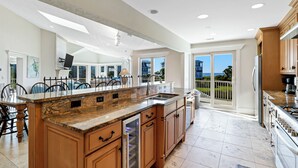 Una cocina amplia con una isla grande, armarios de madera y vistas al exterior.