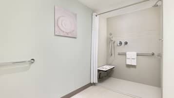A modern bathroom with a glass shower enclosure, a towel rack, and a wall-mounted artwork.