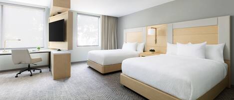 A hotel room with a bed, a desk, and a chair.