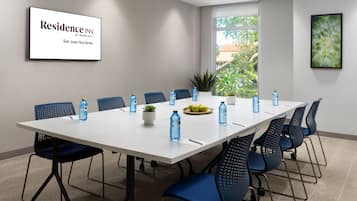 A conference room with a long table, blue chairs, water bottles, and a plant.