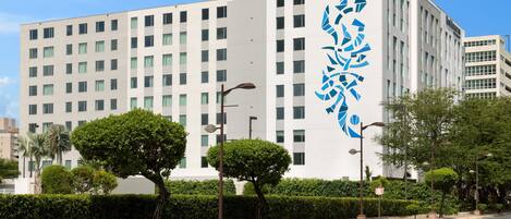 Un bâtiment moderne avec un grand logo sur le côté, de nombreuses fenêtres et un ciel dégagé.