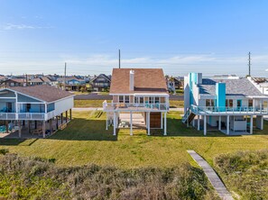 A beachfront property with a central house featuring a balcony, surrounded by other houses.