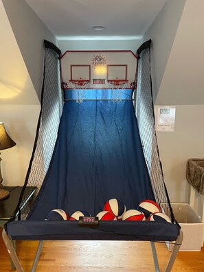 Una pequeña cancha de baloncesto cubierta con suelo azul, dos aros de baloncesto y un marcador.