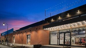 A modern building with a glass entrance, outdoor seating, and a brick facade. - Evo Hotel (Salt Lake City)