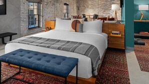 A modern bedroom with a large bed, a bench, a desk, and a TV. - Evo Hotel (Salt Lake City)