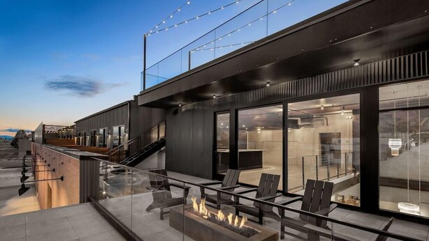 A modern outdoor seating area with fire pits, glass railings, and a staircase leading to an upper level. - Evo Hotel (Salt Lake City)
