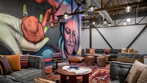 A modern interior with a mural, multiple seating areas, and a large rug. - Evo Hotel (Salt Lake City)
