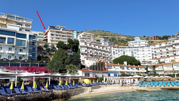 A coastal hotel with multiple floors, outdoor seating with umbrellas, and a view of the sea. - Modern, stylish apt by the sea with large balcony, sea view, close to the center (Sarandë)