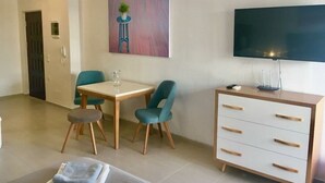 A modern living room with a dining area, a flat-screen TV, and a painting on the wall. - Modern, stylish apt by the sea with large balcony, sea view, close to the center (Sarandë)