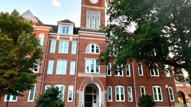 A large brick building with a prominent clock tower, arched windows, and a central entrance. - New 3 Bdr Home - Clemson / Pendleton - Close to Everything (Pendleton)