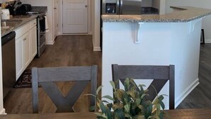 A modern kitchen with white cabinets, a stainless steel refrigerator, and a granite countertop. - New 3 Bdr Home - Clemson / Pendleton - Close to Everything (Pendleton)