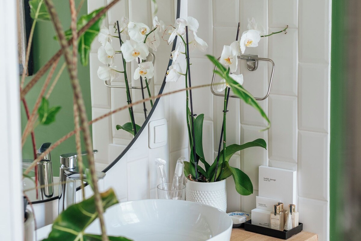 Ein Badezimmer mit Waschbecken in Weiß, grünen Wänden und weißen Fliesen.