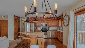 Une cuisine dotée de meubles en bois, d’appareils électroménagers en acier inoxydable, d’un coin bar et d’une table à manger.
