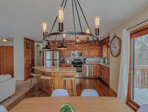 Enjoy cooking in this well-equipped kitchen with a central island, stainless steel appliances, and a large window offering a view of the outdoors.