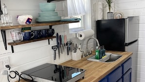 A modern kitchen with a black induction cooktop, blue cabinets, and a wooden countertop. - Tiny Home! With Great Layout!  Unique Stay Nurses Welcomed (Houston)