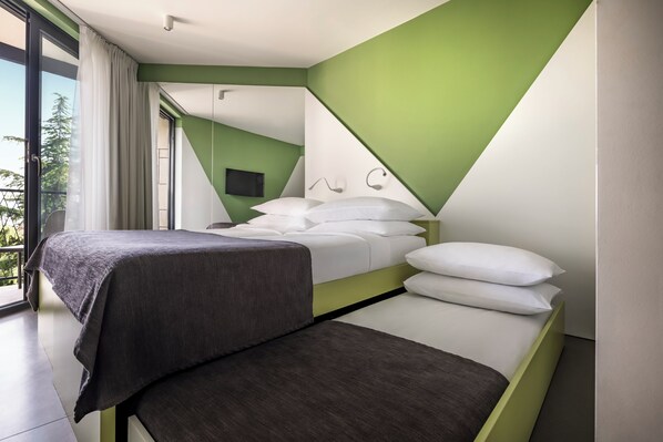 A modern bedroom with a bed, bedside tables, and a view of the outdoors.