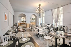 A dining area with tables and chairs, a chandelier, and a view of the kitchen in the background. - Aminess Vival Casa Lisanj (Delnice)