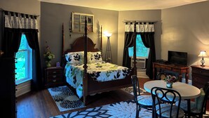 A bedroom with a four-poster bed, a desk with a TV, a dining table with chairs, and a window with curtains. -  Farmhouse in the Country-Perfect Place to Relax and Enjoy Family and Friends! (Lebanon)