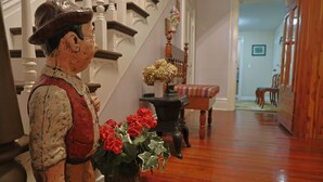 A staircase with a wooden railing and a decorative figure holding a vase of red flowers. -  Farmhouse in the Country-Perfect Place to Relax and Enjoy Family and Friends! (Lebanon)