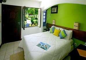 A hotel room with a bed, a window, and a green wall. - Hotel Portaló (Cairu)