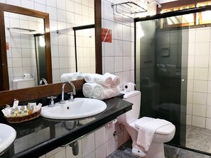 A bathroom with a sink, mirror, towel rack, and a glass-enclosed shower area. - Hotel Portaló (Cairu)