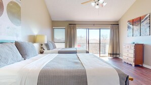 A bedroom with two beds, a dresser, a lamp, and a view of the outdoors. - River City Resorts: C202 along the Comal River (New Braunfels)