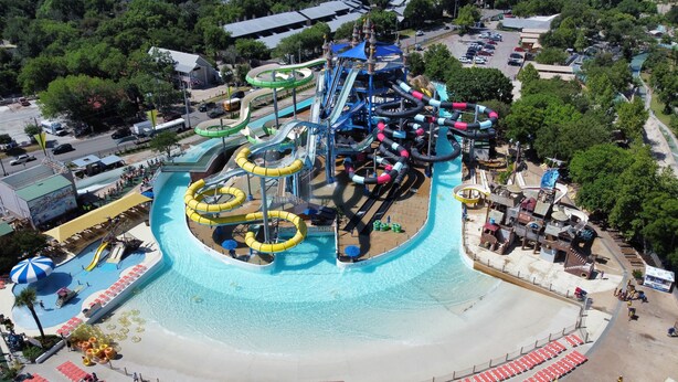 An aerial view of a water park with multiple water slides and pools. - River City Resorts: C202 along the Comal River (New Braunfels)