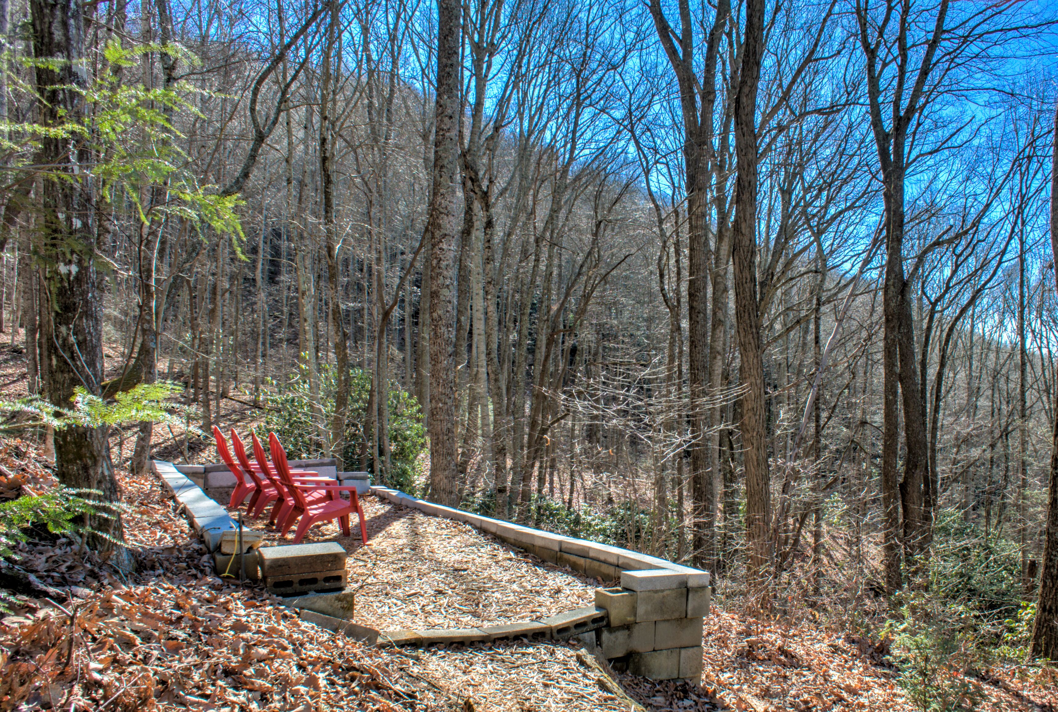 A forested area with a wooden bridge and red chairs.