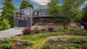 Une maison moderne à deux étages, dotée d’un grand garage, d’un balcon et d’un jardin bien entretenu.