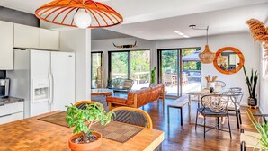 Une cuisine moderne avec des meubles blancs, un réfrigérateur et un coin repas comprenant une table et des chaises en bois.