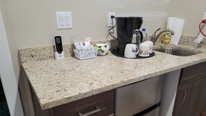 Een keuken met een granieten aanrecht, roestvrijstalen apparatuur, een koffiezetapparaat en diverse keukenbenodigdheden.