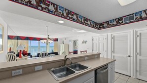 Una cocina moderna con una isla grande, pileta doble y muebles color blanco.