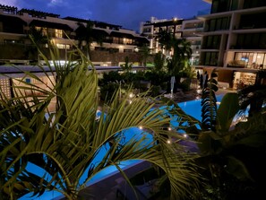 A pool area with palm trees and a building in the background.