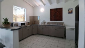 A kitchen with a large island, white cabinets, a microwave, and a dishwasher.