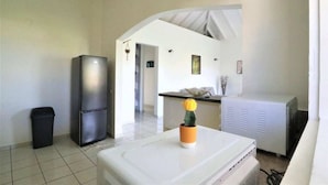 A compact kitchen with a refrigerator, a sink, and a small potted plant.